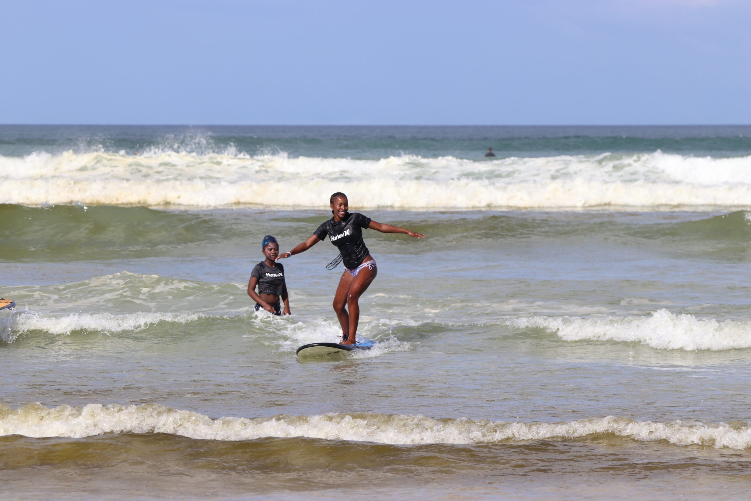 Two girls in the waves on shore learning to surf with Black Girls Surf, Inc.