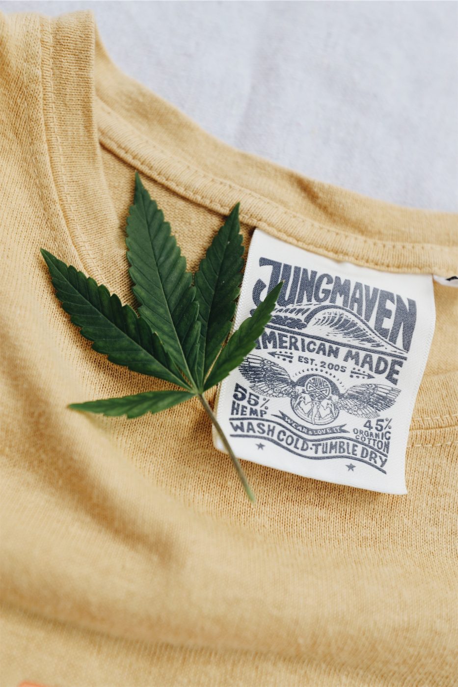 Designed tag on a tshirt made by Jungmaven next to a green hemp leaf.