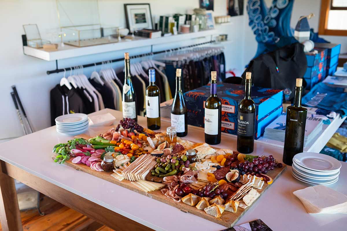 A table set with a varitey of bottles of wine, stacked empty plates and napkins, and a charcuterie board catered by Land Charc Provisions. 