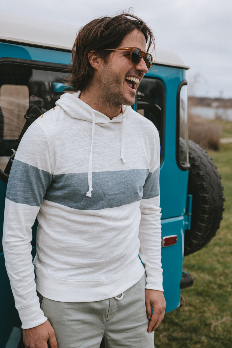 One of the Faherty twins smiling, standing in front of an jeep. 