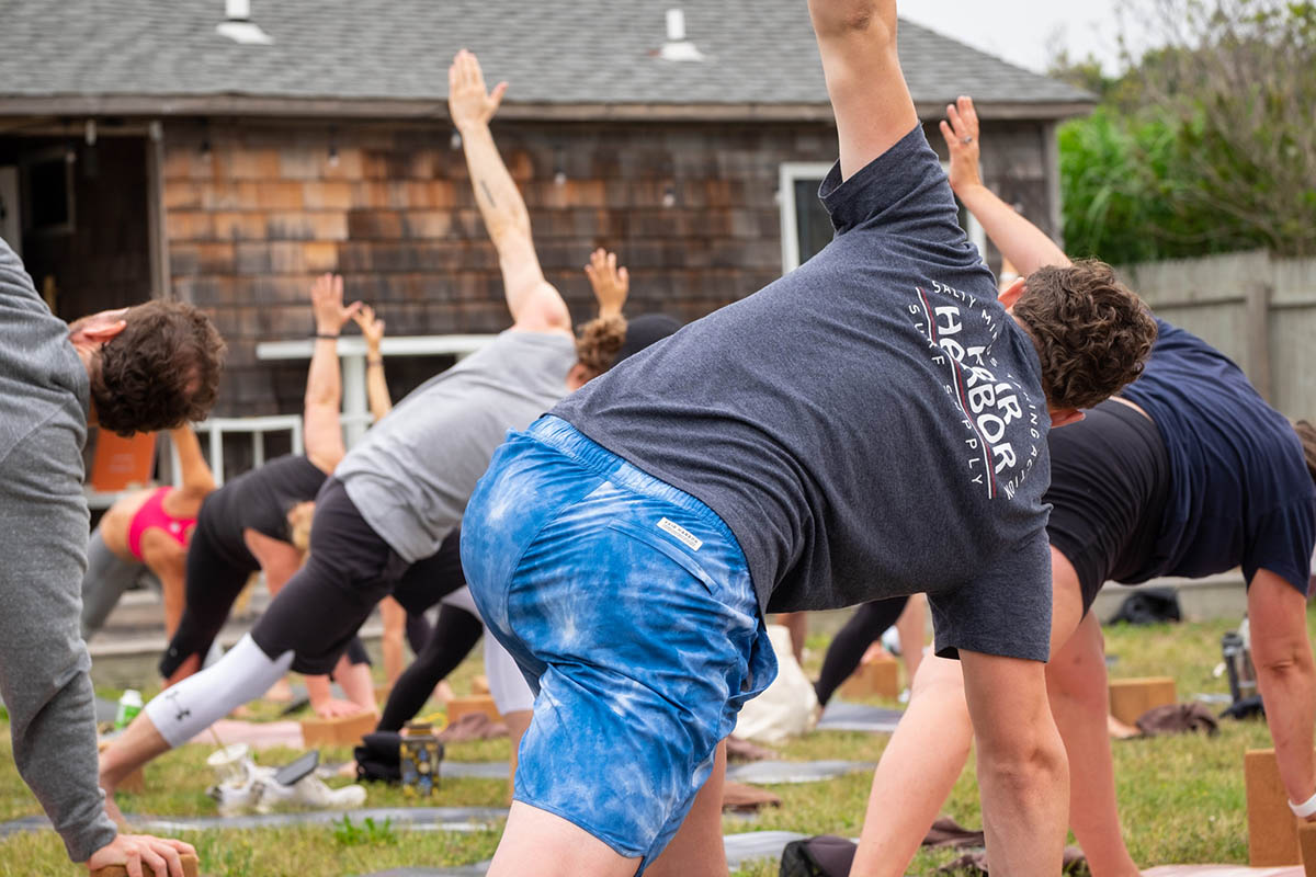 A group of people participate in a yoga class during the Fair Harbor Gin Beach Cleanup and Happy Hour in Montauk