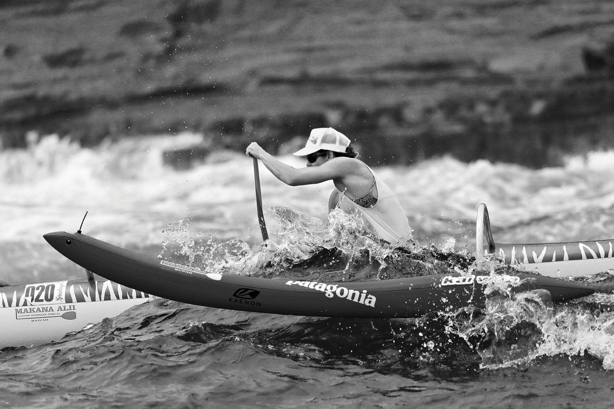 A woman in a canoe padding aggressively in water.