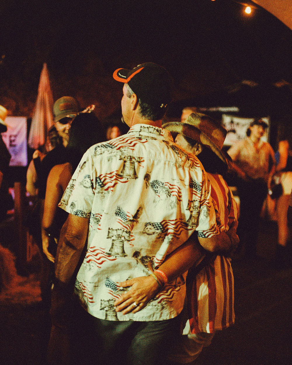 An older couple have the arms wrapped around each other and look off into the distance In photograph of Folsom Rodeo 60th Anniversary by Cameron Munn