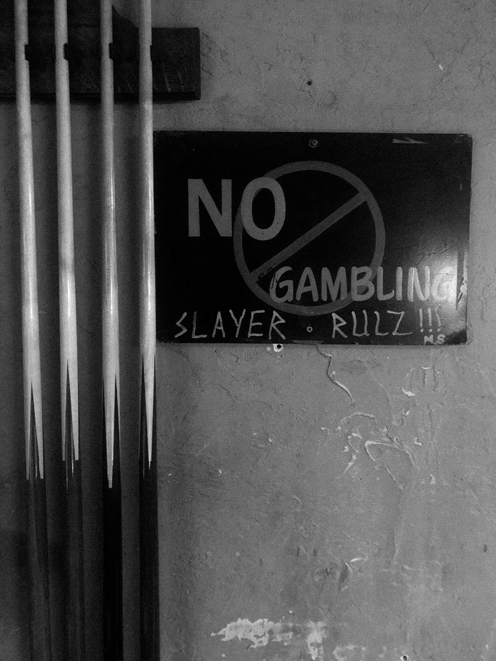 black and white photograph by Gunner Hughes of sign that reads "no gambling" and "slayer rulz"