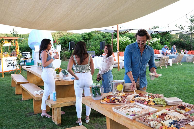 Party attendees help themselves to a table wide charcuterie setup outside at the Tanqueray event at Hero Beach Club in Montauk 