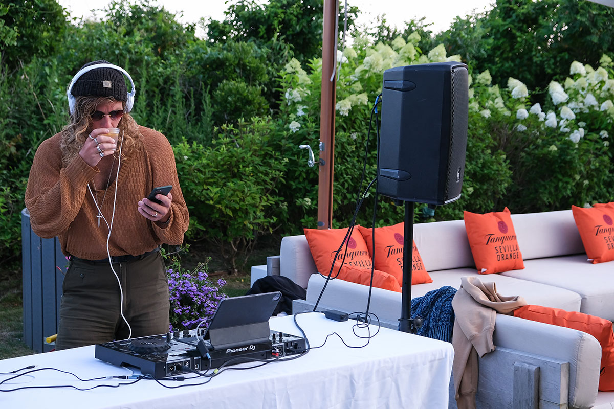 A DJ stands behind is set up on a table at the Tanqueray event at Hero Beach Club in Montauk 