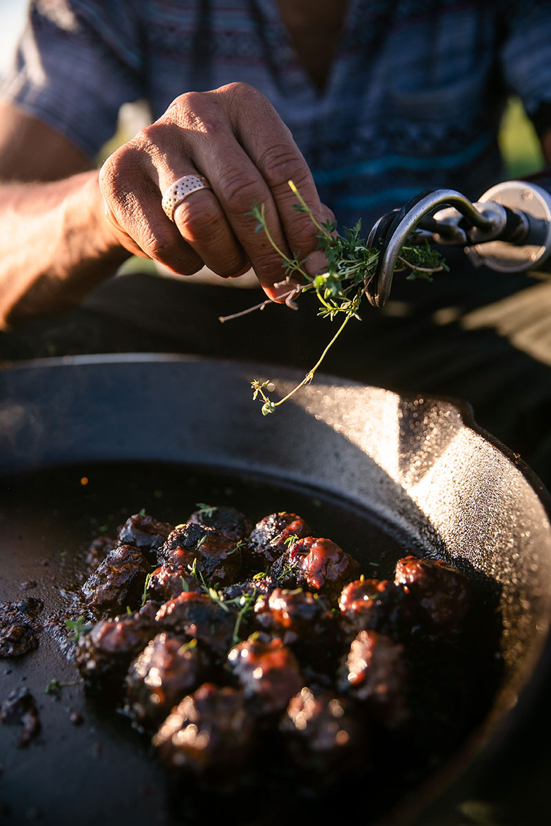 Chef Eduardo Garcia puts herbs atop meatballs in an iron skillet