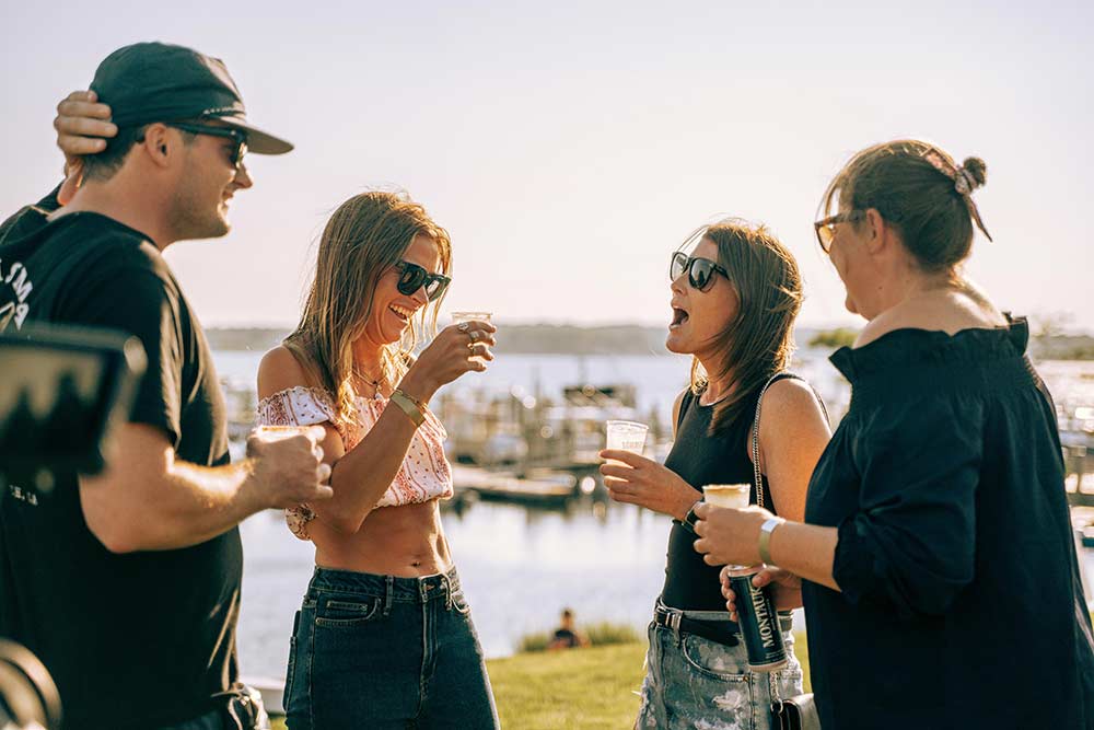 People talking and holding drinks at the Whalebone Magazine Sixth Anniversary party at the Montauk Lake House