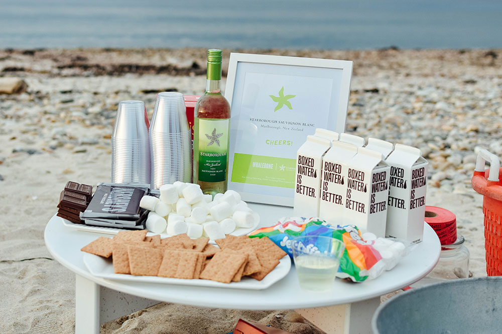 table with wine, water and s'mores supplies out on the beach