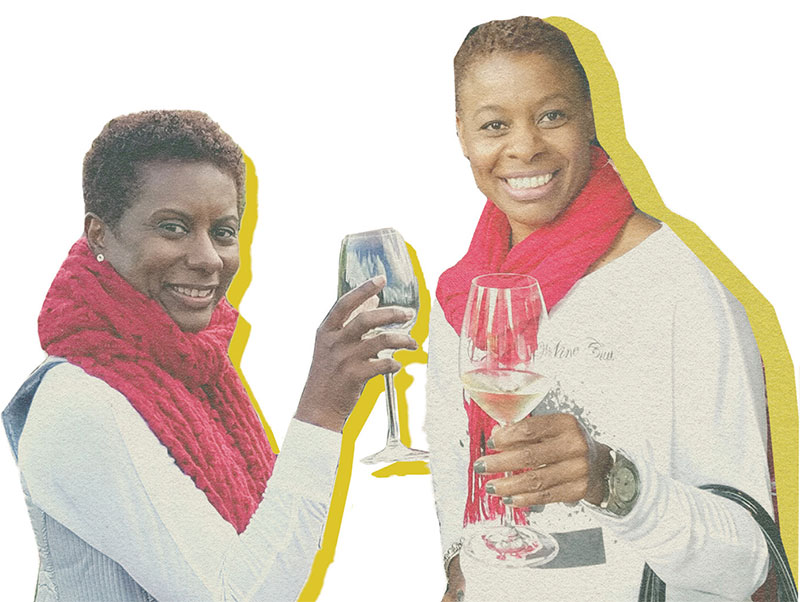 Two women hold wine glasses and look toward the camera, both smiling. Each wears a red scarf. 