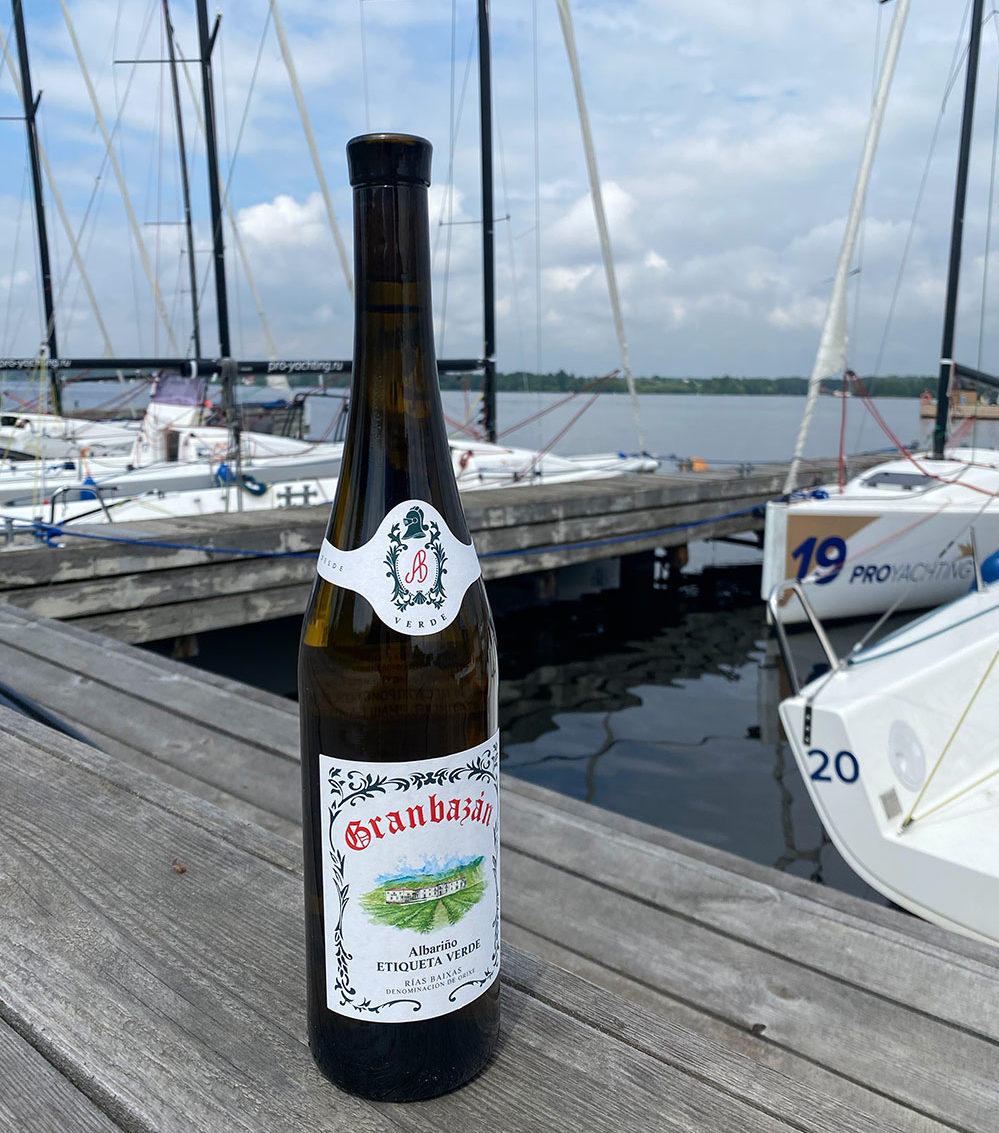 Granbazan Etiqueta Verde Wine on a wood dock with boats floating in the background