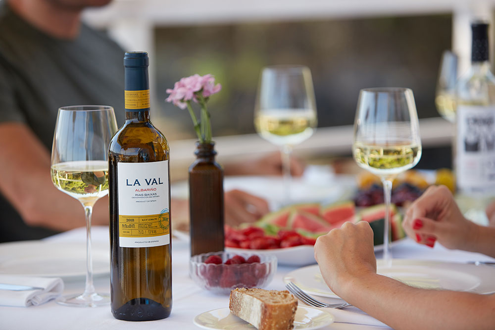 La Val Albarino Wine on a table set with glasses, plates of fruit and bread