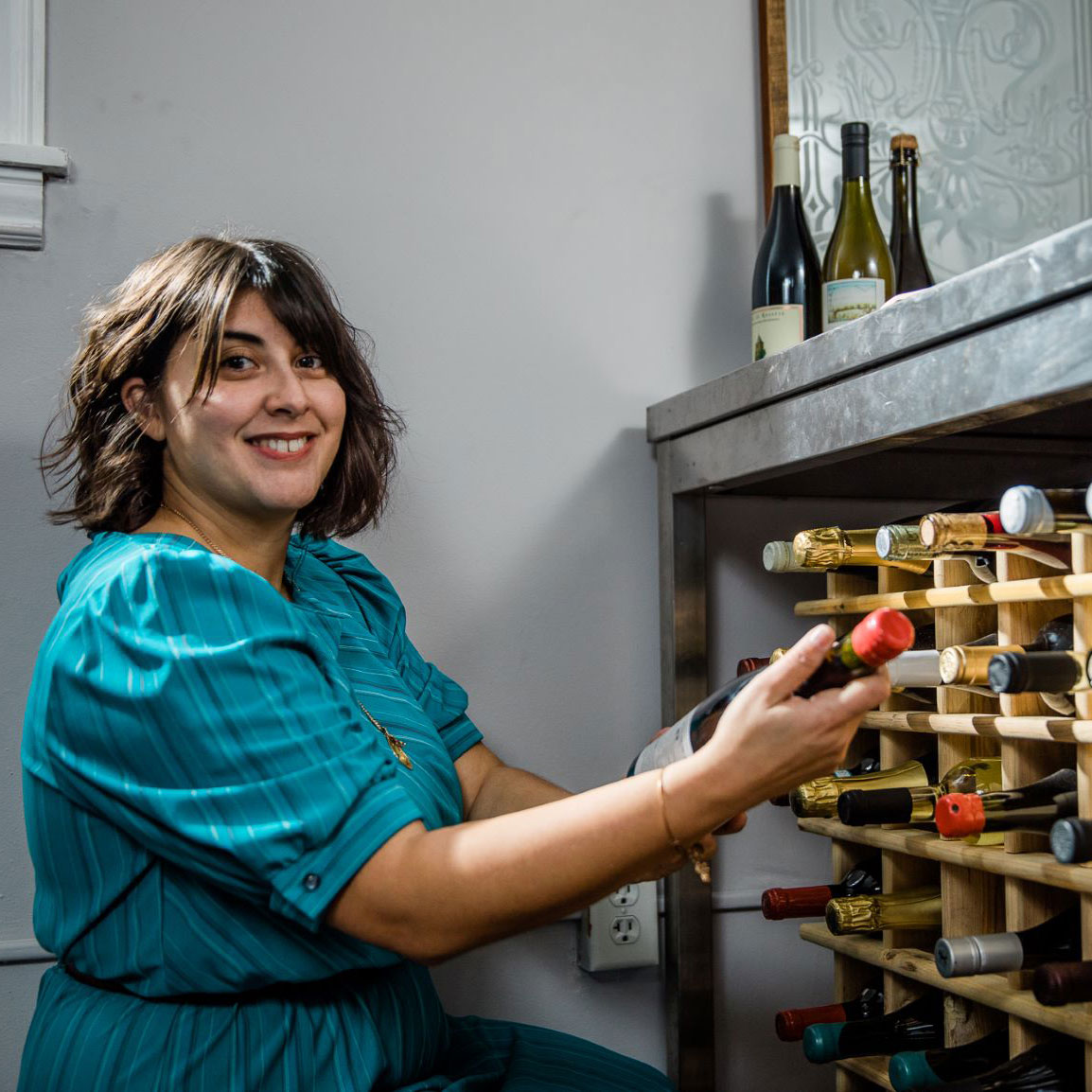 Lourdes, Sommelier, picking wine from shelf
