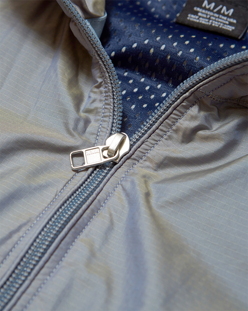 Close up photograph of the zipper on the Rhone Nanoprojects Bowie Windbreaker in Ashley Blue