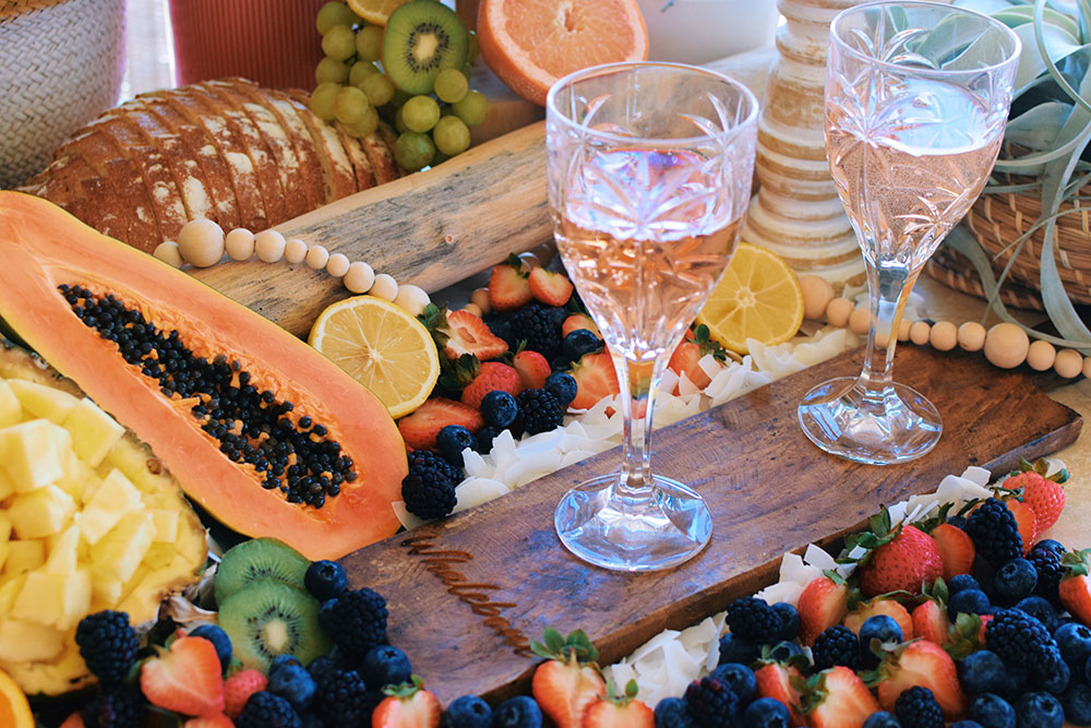 rose glasses on cheese board with fruit