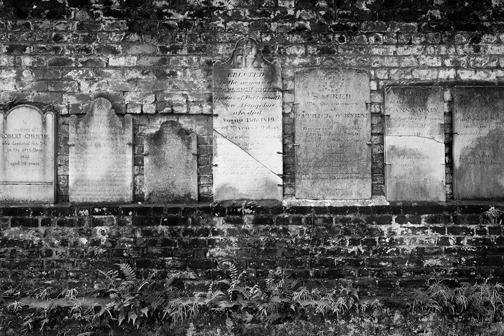 Black and white photo of cemetery tomb stones taken by Gunner Hughes