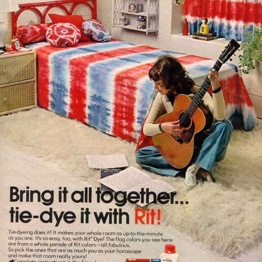 Girl sitting on the floor holding guitar in a room with tie-dyed bed and curtains.