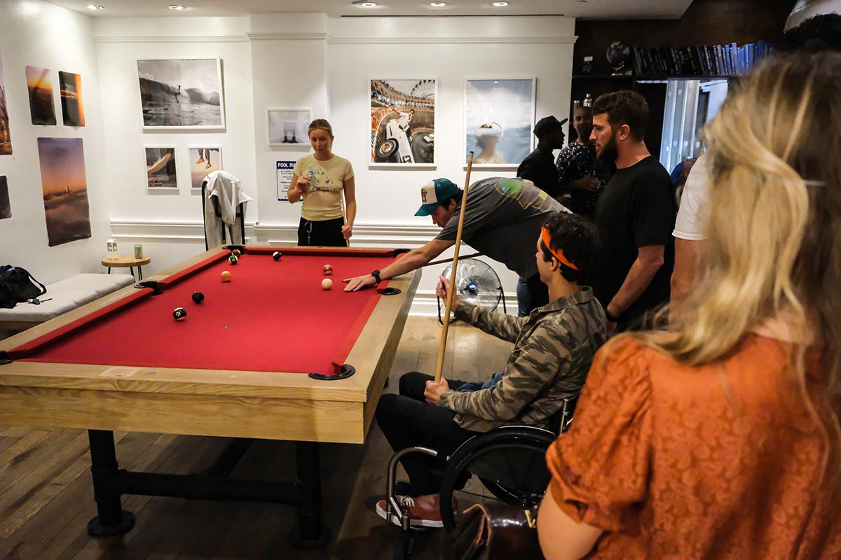People surround a pool table and are playing at the Governors Ball pre-game bash with JuneShine and Whalebone Magazine on Bleecker Street.