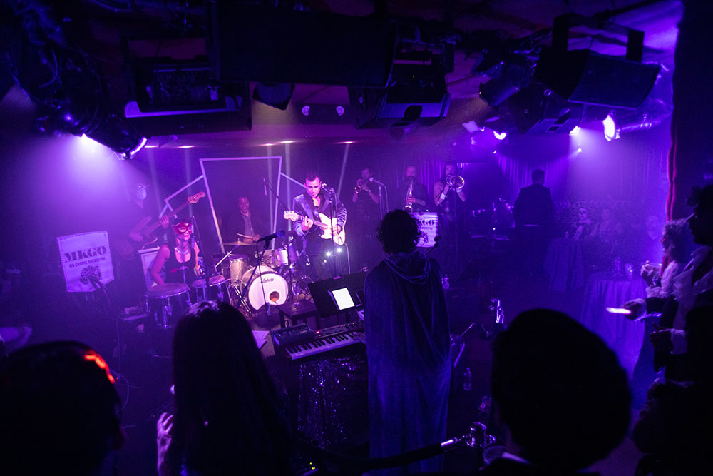 McKittrick Hotel Halloween Party 2021, a band awash in purple light plays to a crowded room
