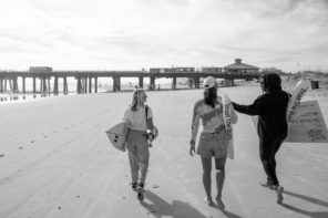 Surfers walking on Jacksonville Beach in black and white