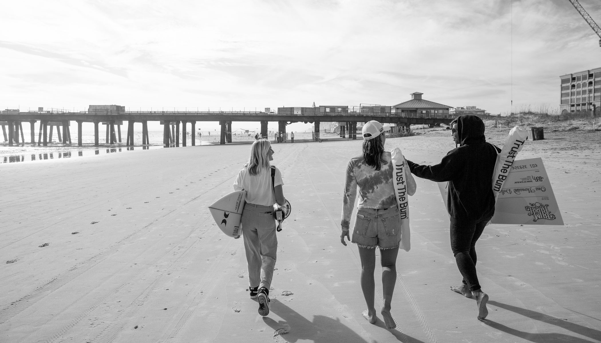 Surfers walking on Jacksonville Beach in black and white