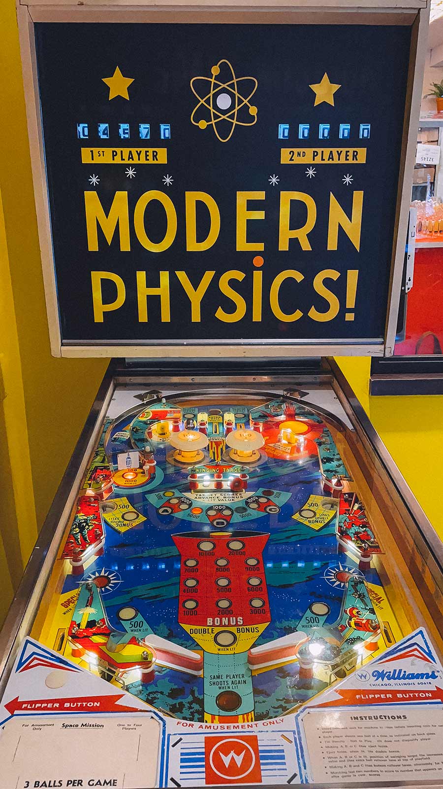 A vintage pinball machine called Modern Physics flashes different colors at Le Sans Blague, the The French Dispatch takeover of Whalebone on Bleecker