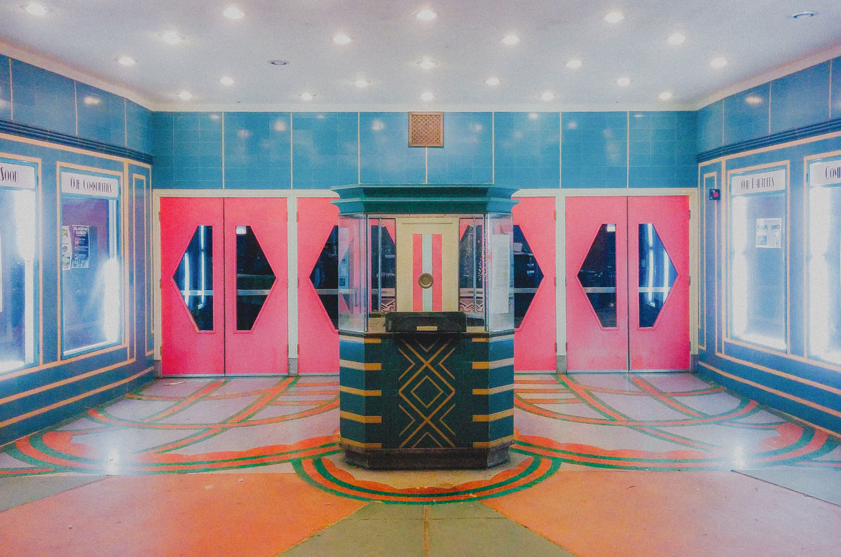 TOWER THEATER interior lobby. Colorful pink doors with pattern green, orange, and cream colored floors.