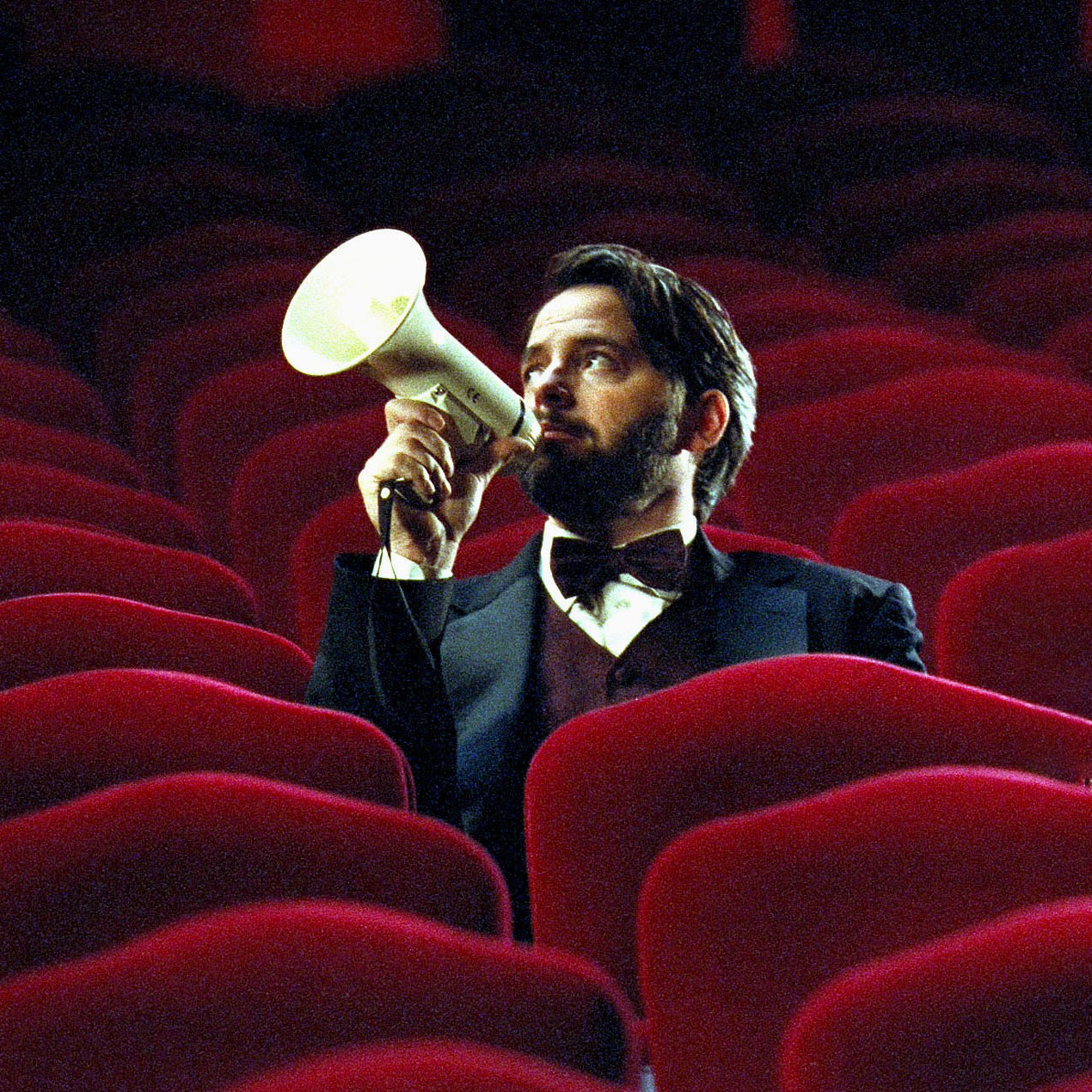 Matthew Broderick with megaphone sitting in red-velvet theater.