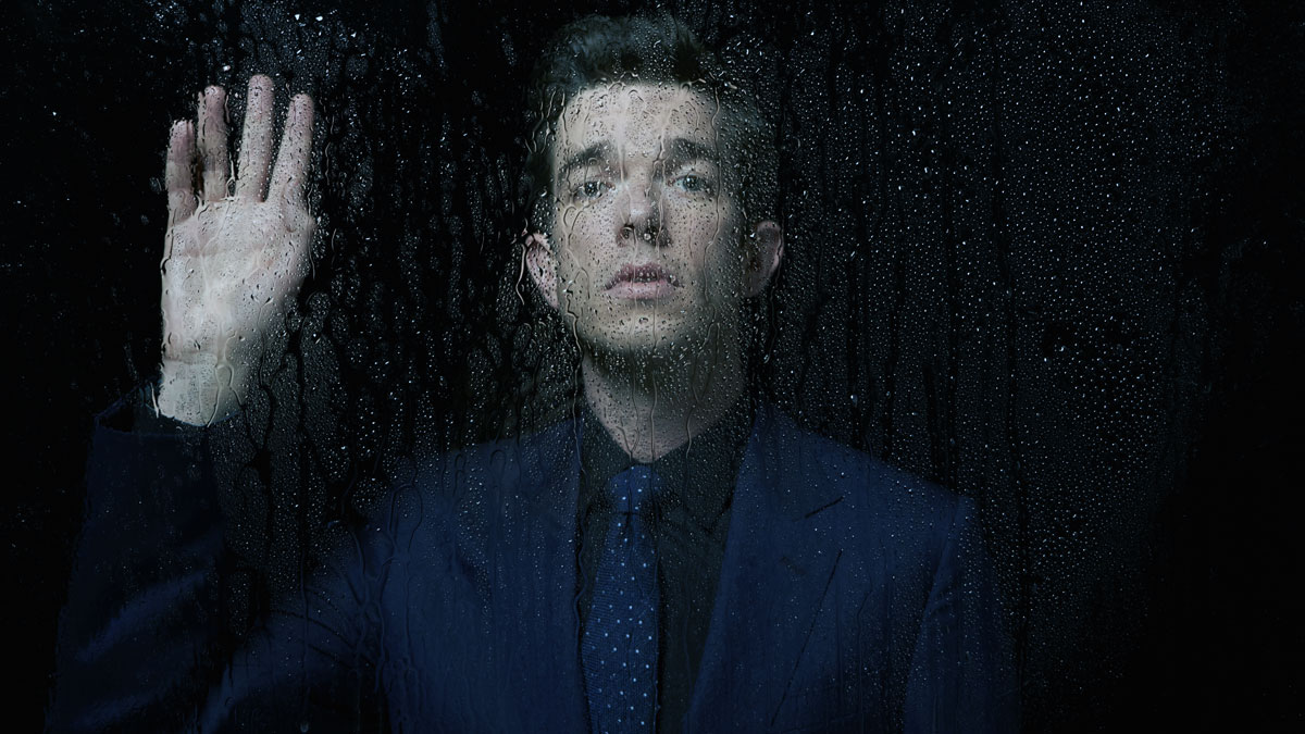 John Mulaney looking out of rainy window, longing for you.