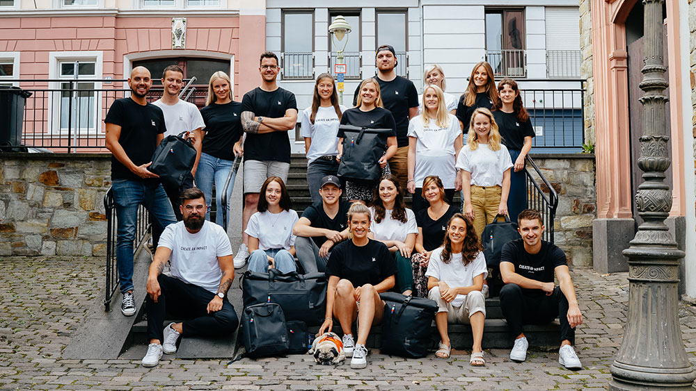 Members of the GOT BAG Team 2020. A mix of men and women dressed casually in tshirts and jeans stand and sit along a stair case, facing the viewer. 