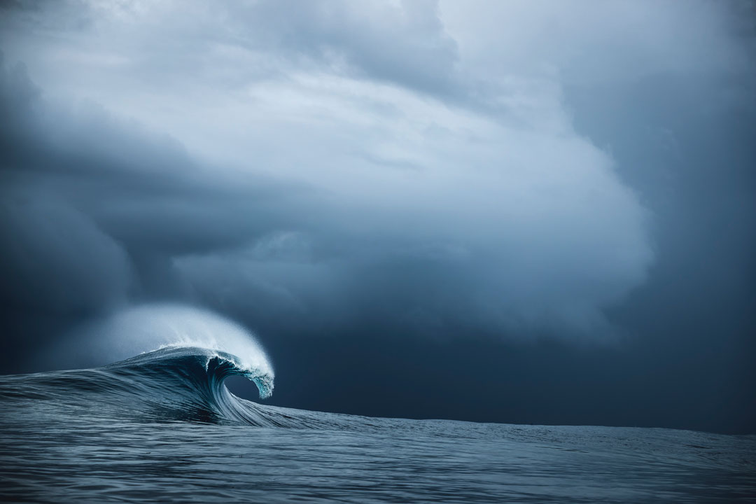 Ben Thouard photograph of a lone wave breaking against the background of stormy skies.