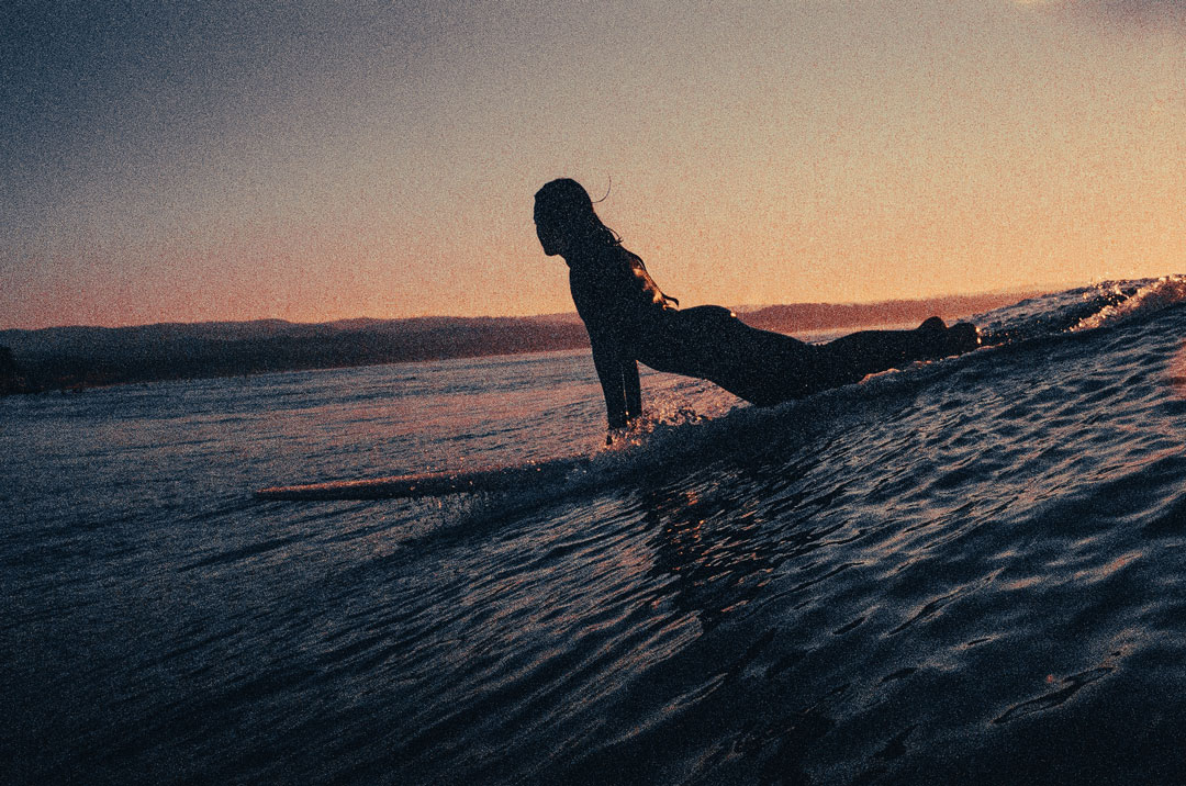 Woman surfing about to catch a wave at sunrise.