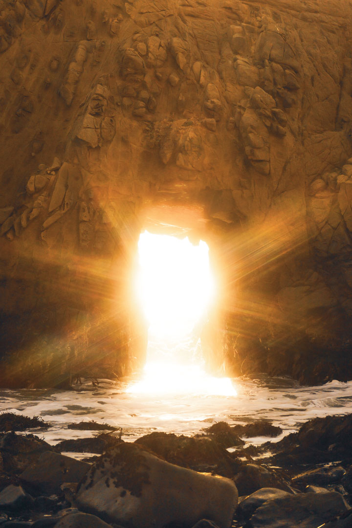 Photograph of sunshine coming through a rock formation