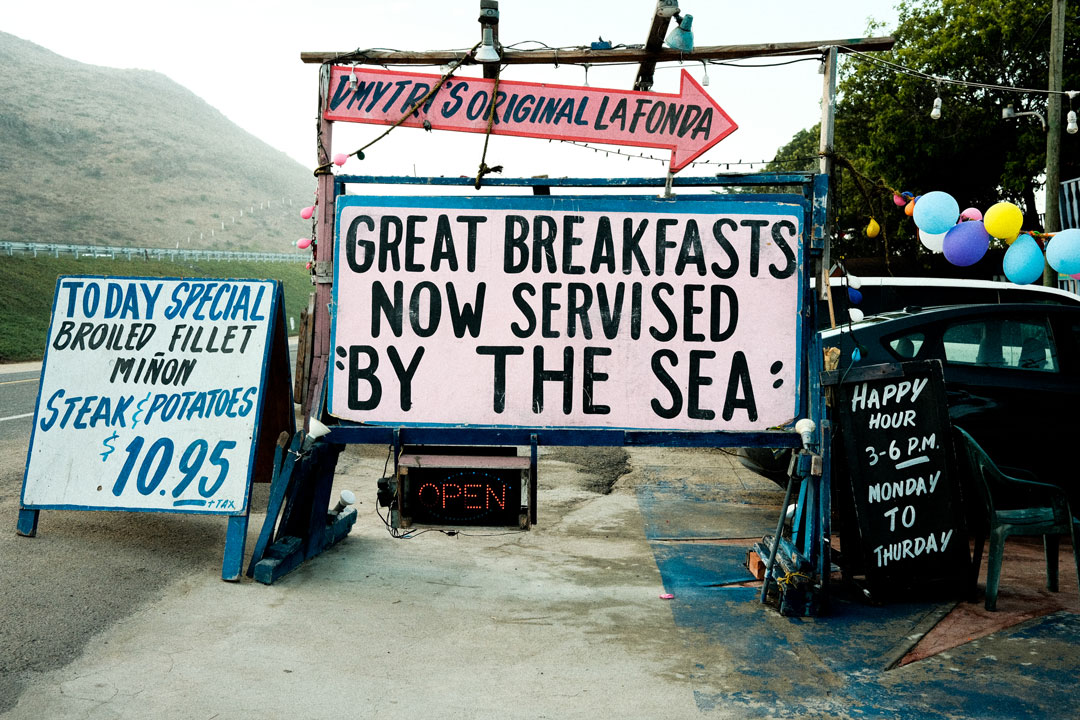 Large color signs in English advertise a great breakfast by the sea.