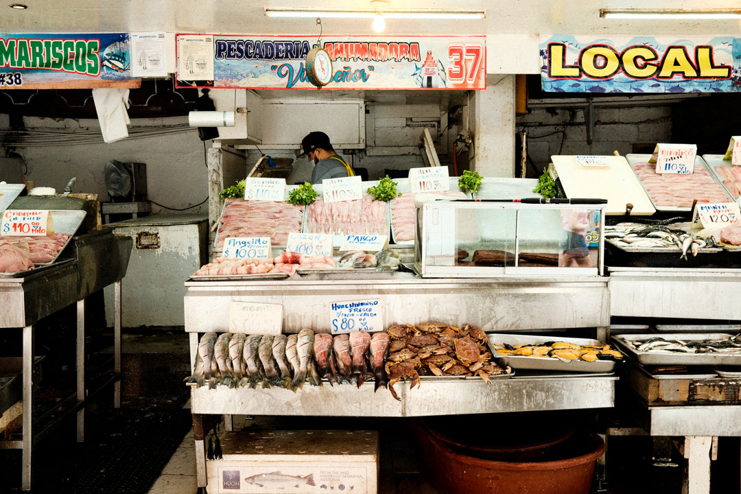 A lone worker stands behind his booth with fish on display and for sale at a local wet market. 