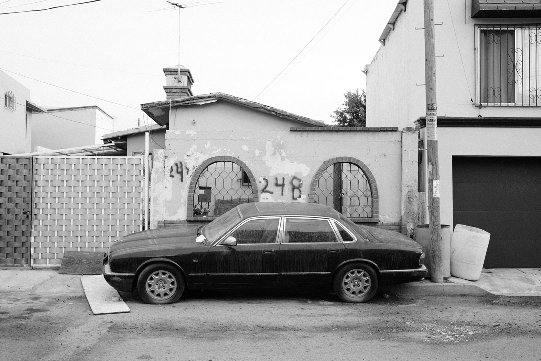 A parked car in front of a small house.