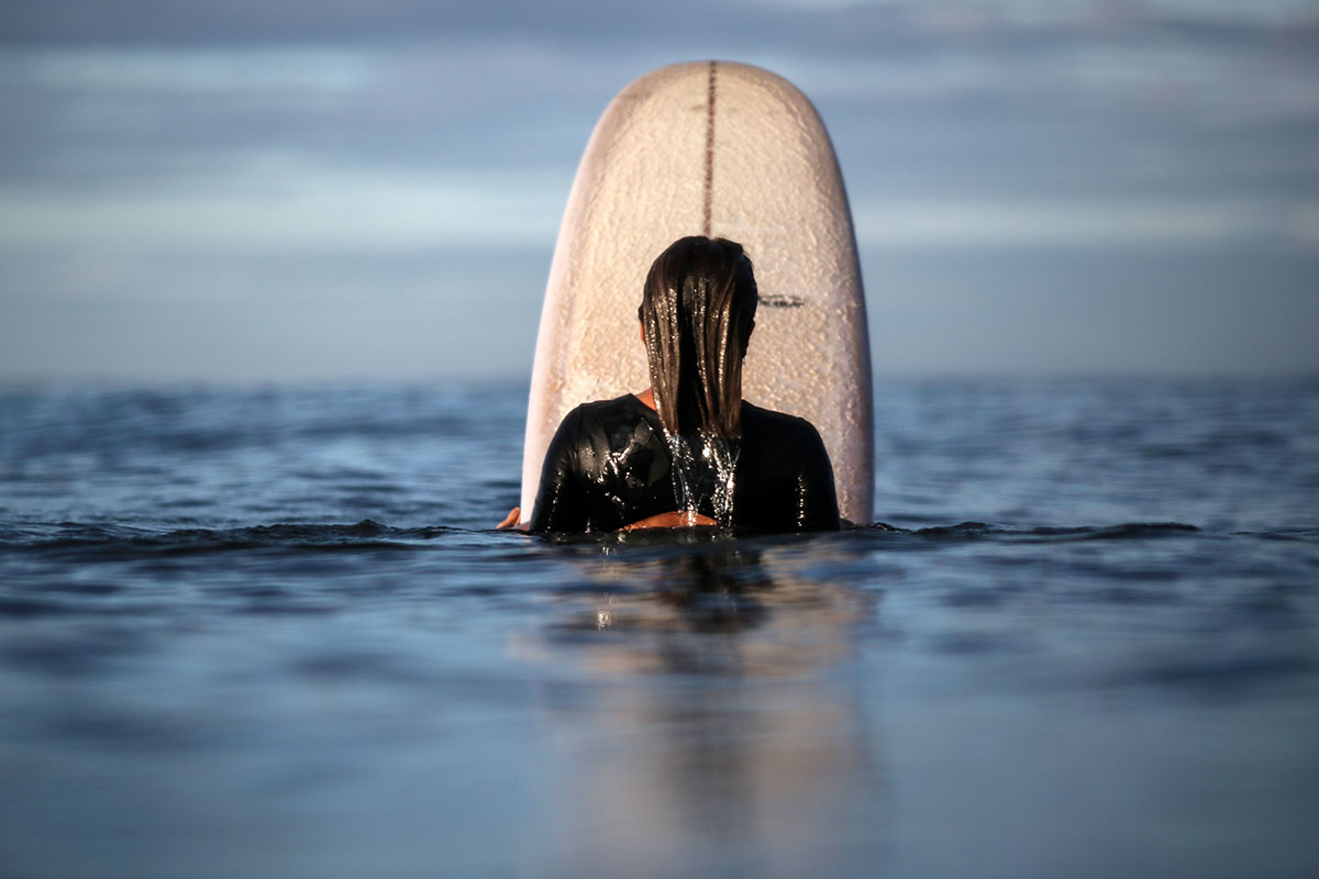 Nature of Surf Women, woman sitting on surfboard in water
