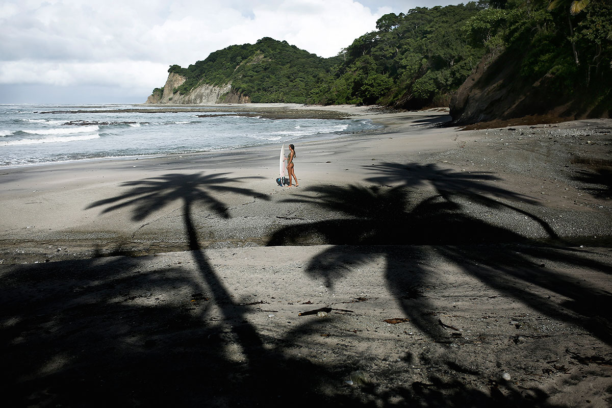 Nature of Surf Women, woman standing on beach with palm tree shadows