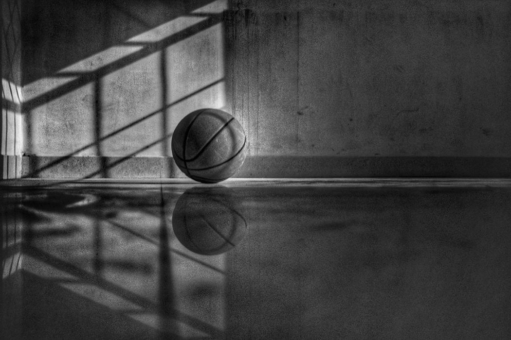 black and white image of basketball sitting on ground of empty court