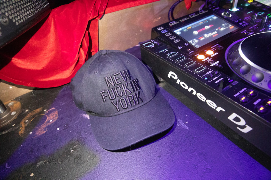 Photo of a black baseball cap that read "New Fuckin' York; sitting next to a DJ turn table.