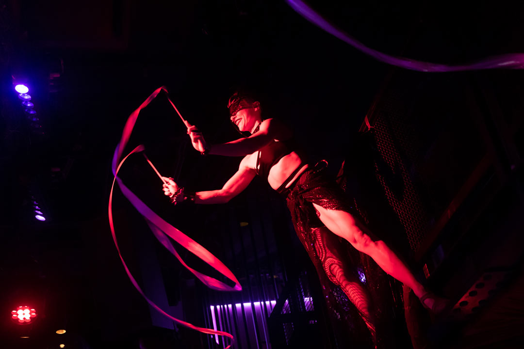 Photo of a club performer twirling around ribbons attached to small sticks
