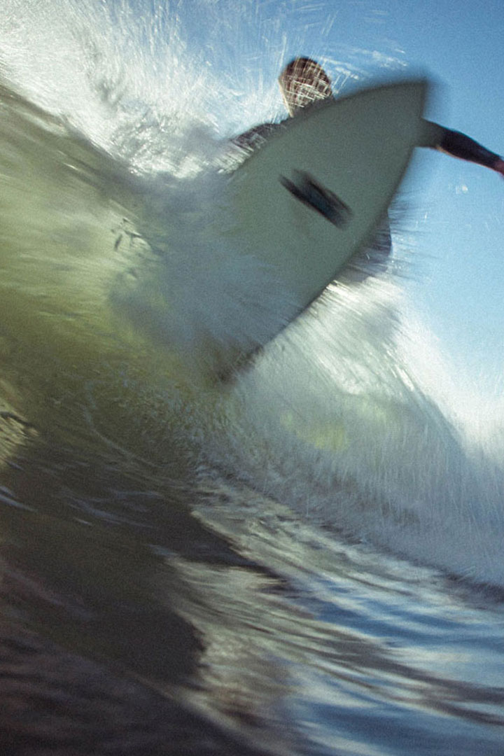 Blurred action shot underneath the board of a surfer while they're surfing.