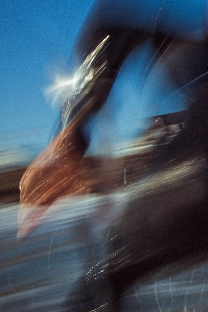 Blurred close up image of a surfer's arm and leg as they're riding wave.