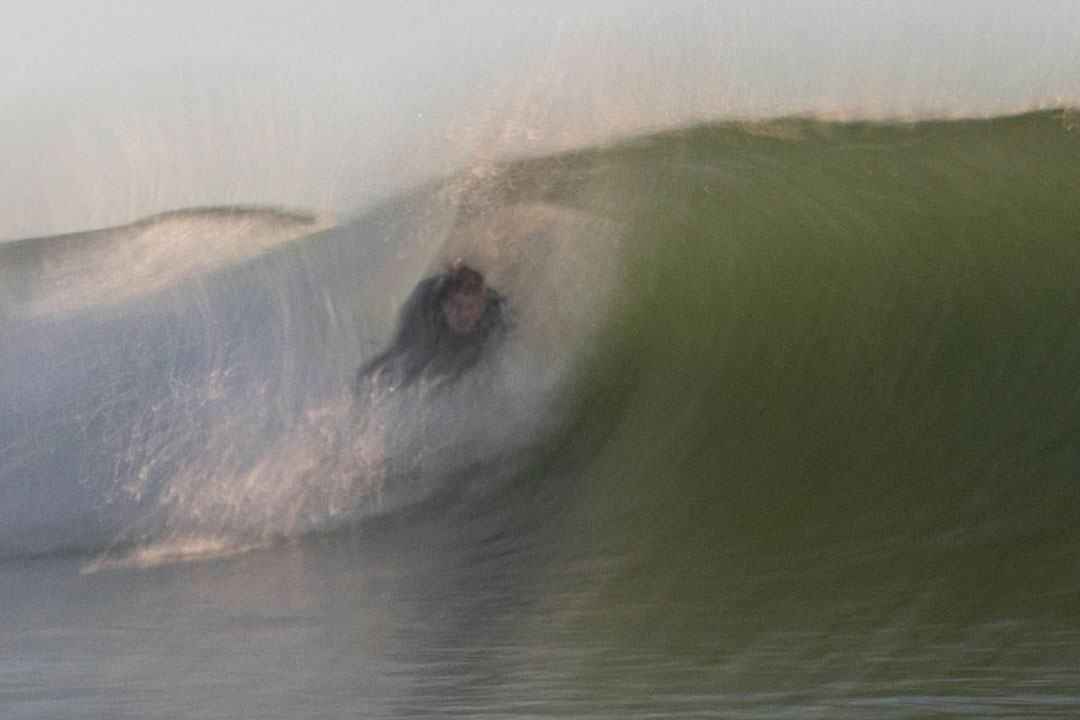 Blurred action shot of a surfer riding through a wave barrel.