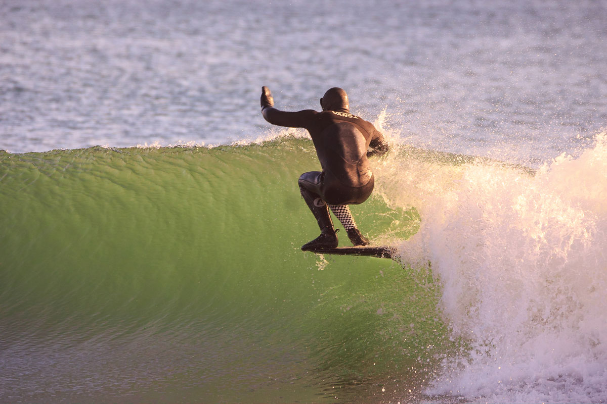 Dean Petty balancing on tip of surfboard on green wave