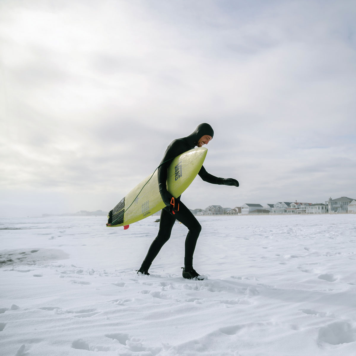 Surfer holding surfboard in snow