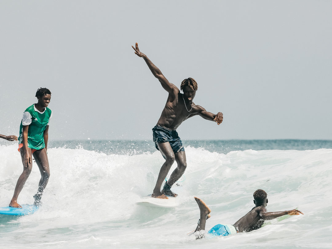Photo of three surfers having fun in the waves. One paddles into the waves while the other two cruise next to each other.