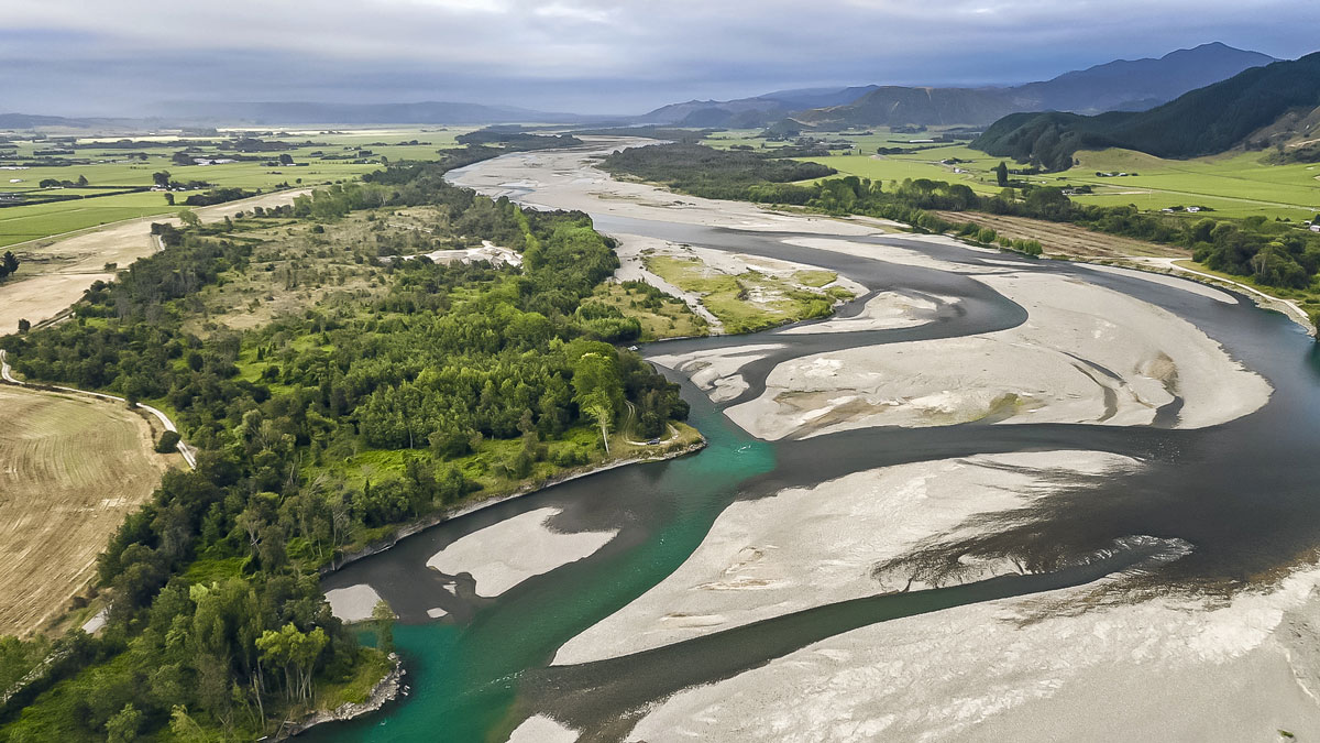 aerial photo of Wairau River winding int the distance. Mountains sit to the right and in the background.