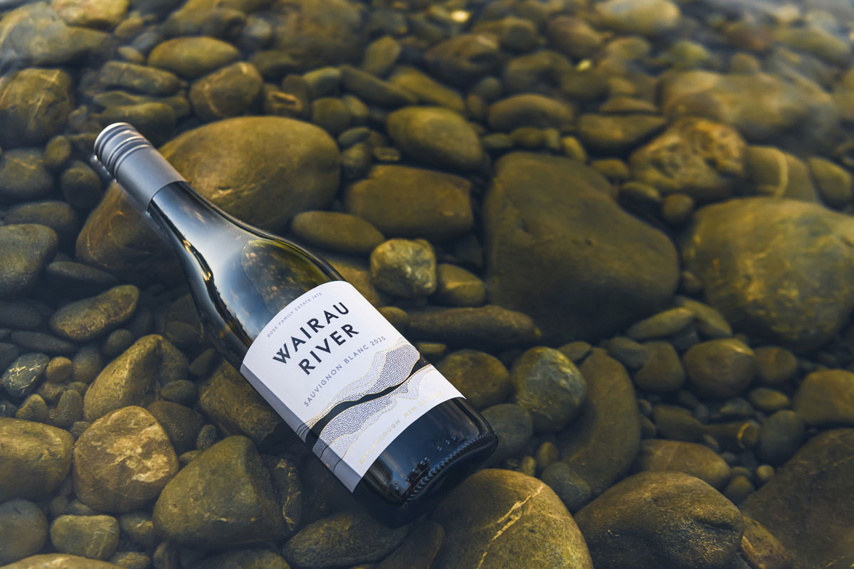 Wairau River bottle of wine sitting in a pebble river 