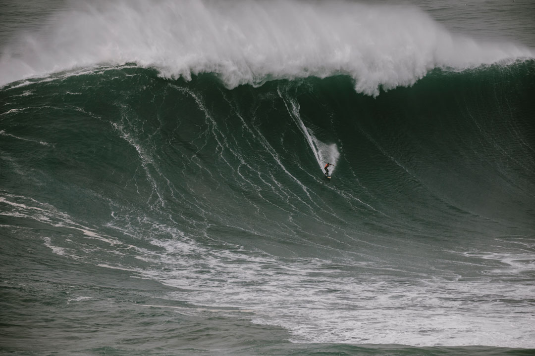 NIc Von Rupp racing down the middle of a tall wave before it crashes over him.